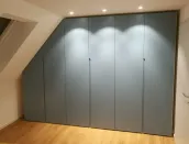 Armario bajo techo inclinado: cada techo tiene una pendiente diferente, por lo que ofrecemos nuestro configurador, que se adapta perfectamente a sus medidas para crear un diseño de armario práctico y funcional, personalizado según sus necesidades. Todo está cuidadosamente oculto detrás de puertas de color personalizado. 

Este armario está instalado en la casa de nuestro cliente en Braunschweig, Alemania - diseño RAL 2406015 lacado mate con tiradores integrados.