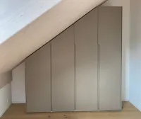 Armoire sous pente: chaque toit a une inclinaison différente, c’est pourquoi nous proposons notre configurateur, qui s’adapte parfaitement à vos mesures pour créer un design d’armoire pratique et fonctionnel, personnalisé selon vos besoins. Tout est soigneusement dissimulé derrière des portes aux couleurs personnalisées. 
Cette armoire est installée dans la maison de notre client à Watt, Suisse - FB 243 Charleston Gray laqué mat avec poignées intégrées.