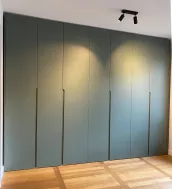 Armario a medida: Instalado en el dormitorio de nuestro cliente en Berlín, Alemania, este color verde varía según la luz (luz natural o iluminación artificial).

Con una iluminación cálida en la habitación y los reflejos del suelo de madera, adquiere un tono verde suave y cálido (como se muestra en la imagen), creando un ambiente acogedor y naturalmente relajante.

Este armario tiene un acabado en laca mate FB 47 green smoke con tiradores integrados.

Las dimensiones exactas de este armario son: 350,7 cm de ancho, 266 cm de alto y 61 cm de profundidad.